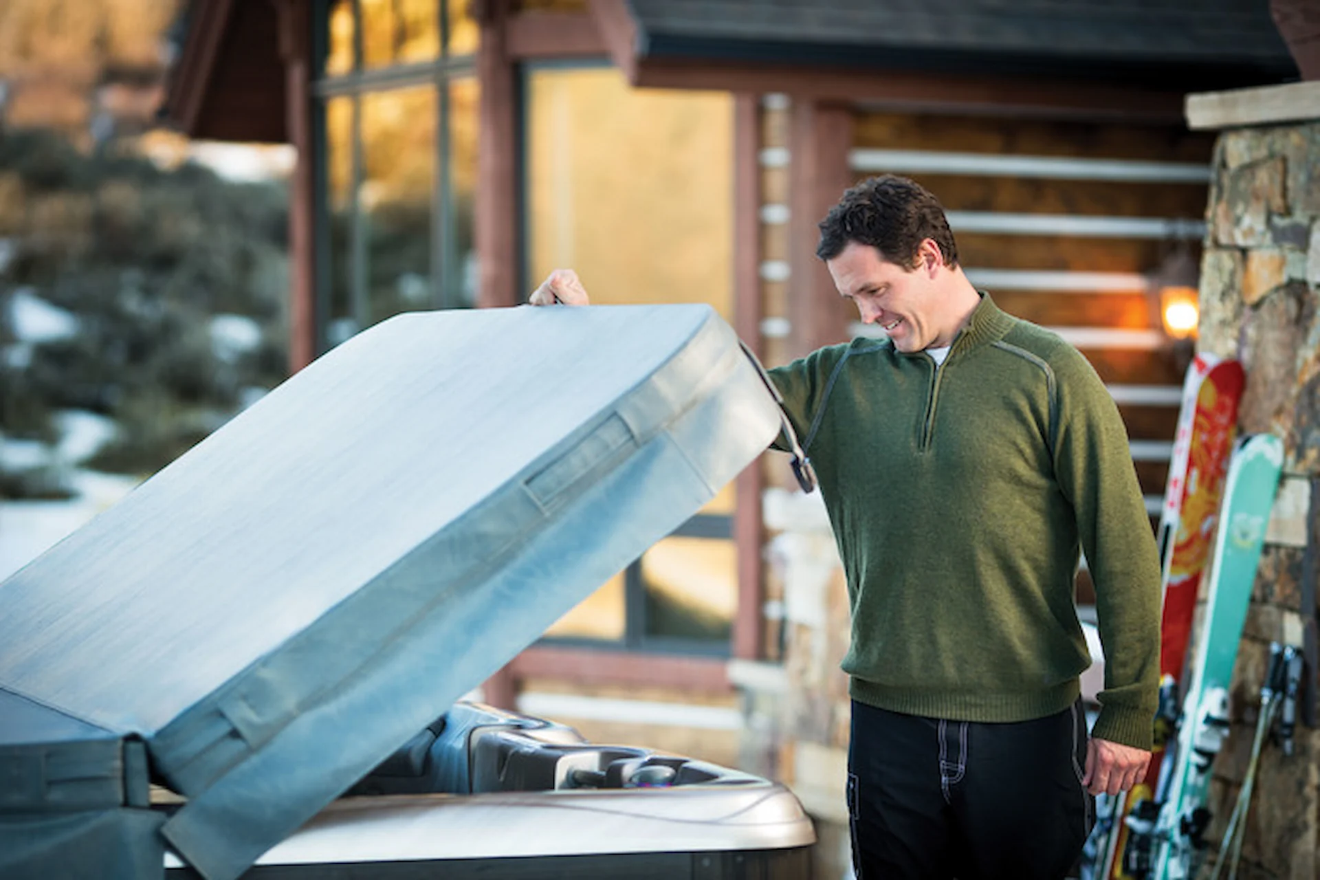 Spa owner lifts a vinyl spa cover as it hinges at its middle.