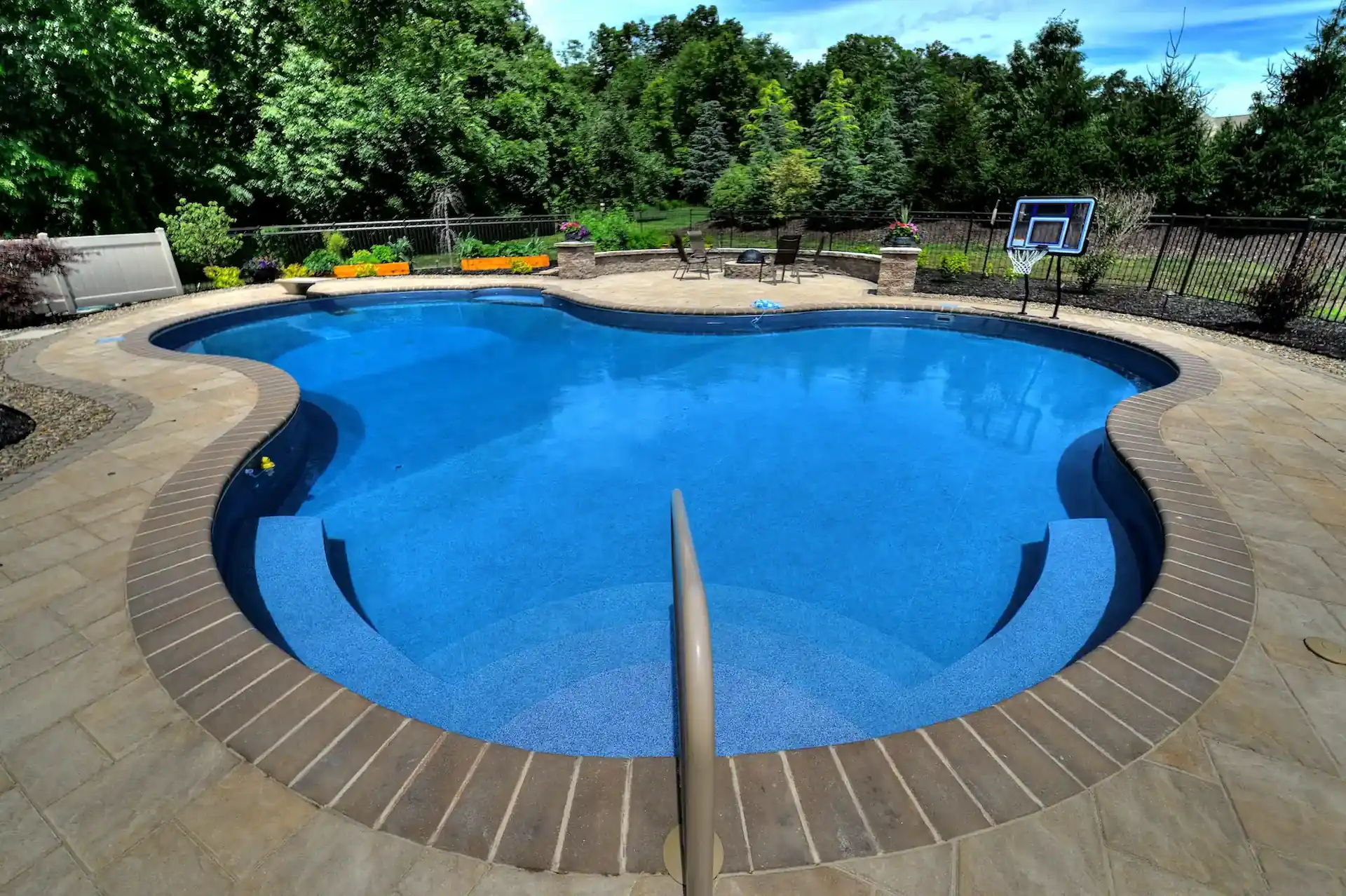 A curved blue pool with blue vinyl pool liner built by Goodall Pools & Spas sits open in the daylight. In pools like these